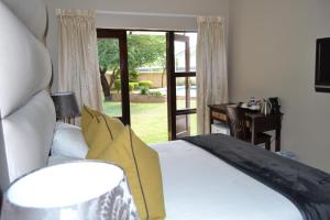 Schlafzimmer mit einem Bett und einer Glasschiebetür in der Unterkunft The Capital Guest House in Gaborone