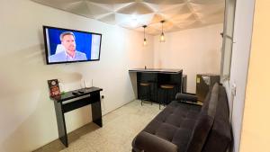 sala de estar con sofá y TV en la pared en Acogedor apartamento familiar con balcón, en Líbano