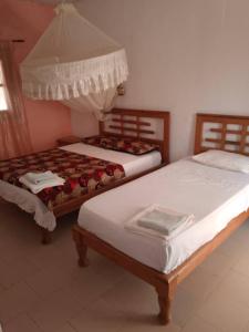 Duas camas sentadas uma ao lado da outra num quarto em Hôtel évasion pêche djilor île sine saloum em Fatick