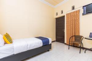 a bedroom with a bed and a chair and a door at SPOT ON 1990 Pondok Ripuji in Makassar