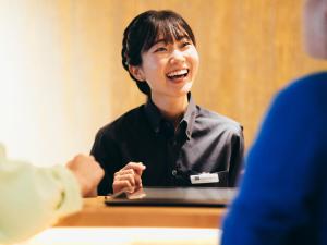a woman laughing while sitting at a table with a laptop at MIMARU KYOTO STATION in Kyoto