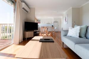 Una sala de estar con un sofá azul y una mesa. en Beautiful Sunny Home: Close to the CBD & Gorge, en Royal Park