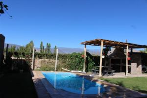 a pool with a pergola next to a house at ANJANA Cabaña con pileta y vista a la pre cordillera in Ullún