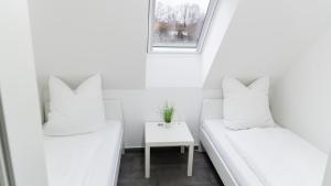 two white beds in a small room with a table at Ferienwohnung Milchverliebt in Osten