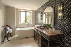 ein Badezimmer mit einer Badewanne, einem Waschbecken und einem Spiegel in der Unterkunft Little Residence- A Boutique Hotel & Spa in Hoi An
