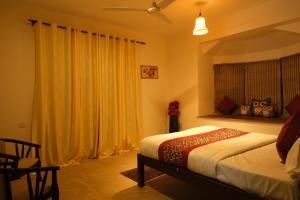 a bedroom with a bed and a window with yellow curtains at 2 BHK beach goan villa with pool calangute in Calangute