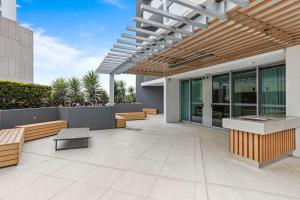 an outdoor patio with benches and a wooden pergola at Cosy 1-Bed Unit with a Gym, BBQ Area, Spa and Pool in Brisbane