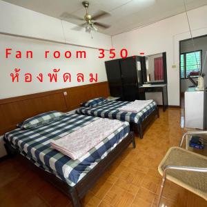 2 camas en una habitación con un cartel en la pared en Thaen Thong Hotel en Lamphun