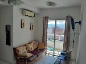 a living room with a couch and a large window at Eduardo Gimenes Palazzi in São Vicente