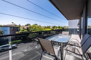 uma varanda com uma mesa e cadeiras e vista para uma rua em Modern 2br Apartment With Free Carpark And Pool em Melbourne