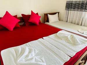 two beds with red and white pillows in a room at Blue Lotus Garden Hotel piliyandala in Colombo