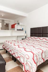 um quarto com uma cama com um edredão vermelho e branco em Hermoso departamento en Oaxaca con estacionamiento em Oaxaca de Juárez