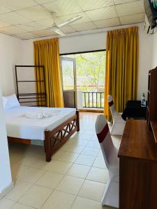 a bedroom with a bed and chairs and a balcony at Blue Lotus Garden Hotel piliyandala in Colombo