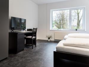a bedroom with a desk and a tv and a bed at Gästehaus Moorblick in Osten