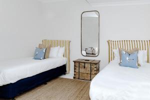 a bedroom with two beds and a mirror at The Patonga Cottage in Patonga Beach