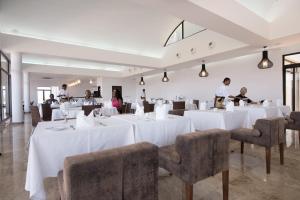 a dining room with white tables and chairs and people at Hotel Vip Executive Tete in Vila-de-Santiago-Maior