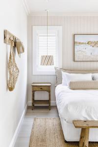 - une chambre blanche avec un lit et une table dans l'établissement Bay Cottage, à Patonga Beach