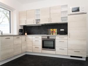 a kitchen with wooden cabinets and a microwave at Gästehaus Moorblick in Osten