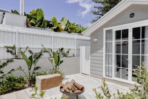 een achtertuin met een wit huis met planten bij Bay Cottage in Patonga Beach