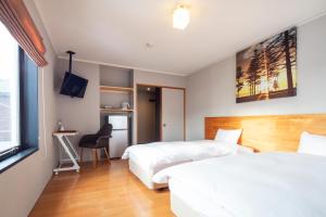 Habitación de hotel con 2 camas y escritorio en M Lodge, en Niseko