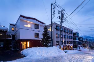 un edificio con un montón de nieve delante de él en M Lodge, en Niseko