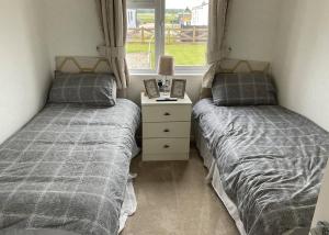 two beds sitting next to a window in a bedroom at Royal Arch Park in Fettercairn