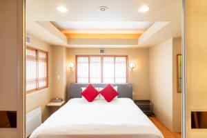 ニセコ町にあるエム ホテル 二セコのベッドルーム1室(赤い枕2つ付きのベッド1台付)