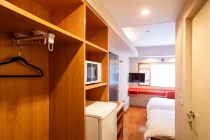 a small room with a bed and a microwave at M Hotel Niseko in Kutchan