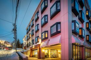 un edificio rosa su una strada di notte di M Hotel Niseko a Niseko