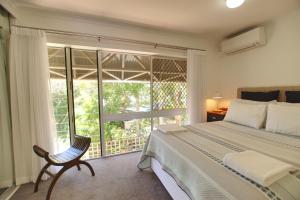 um quarto com uma cama, uma cadeira e uma janela em Raintrees Moffat Beach em Caloundra