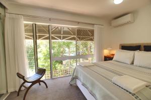 a bedroom with a bed and a chair and a window at Raintrees Moffat Beach in Caloundra