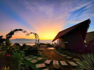 een zonsondergang achter een huis met een boog in een tuin bij Farm Ridge by Desmond Farm in Sampaloc