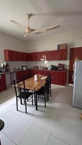 eine Küche mit einem Holztisch mit Stühlen und einem Kühlschrank in der Unterkunft Basil Hostel in Muscat