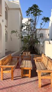 a group of wooden benches sitting next to a building at Basil Hostel in Muscat