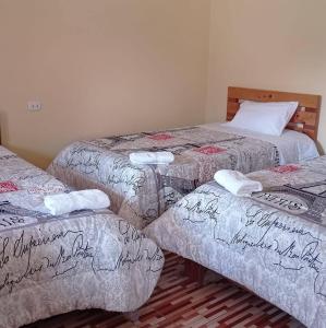 Tres camas en una habitación con escritura. en Hospedaje El Manantial, en Oxapampa