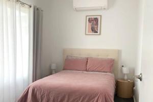 a bedroom with a bed with pink sheets and a window at Family home central to everything in Mildura