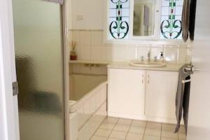 La salle de bains est pourvue d'un lavabo, d'un miroir et d'une douche. dans l'établissement Family home central to everything, à Mildura