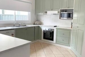 eine Küche mit grünen Schränken, einer Spüle und einer Mikrowelle in der Unterkunft Family home central to everything in Mildura
