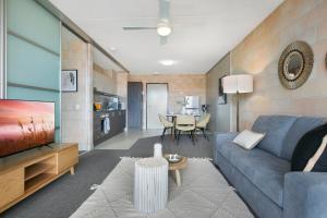 a living room with a blue couch and a tv at Sleek Apartment with Pool and Rooftop Terrace in Gold Coast