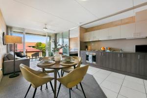 a kitchen and living room with a table and chairs at Sleek Apartment with Pool and Rooftop Terrace in Gold Coast