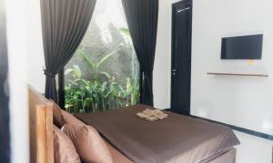 a room with a bed and a window with a window at Escotel Jalak in Canggu