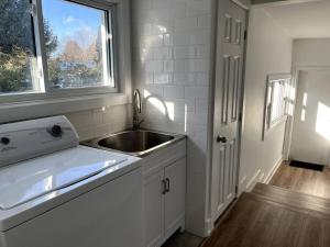 a white kitchen with a sink and a window at New and Cozy Cottage Minutes to Blue Mountain in Meaford +30 photos