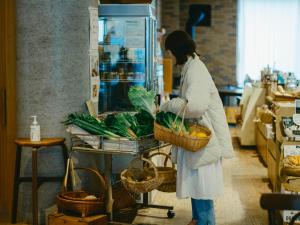 a woman standing in a store with a basket of vegetables at まちごとホテルLOOP 小林 in Makata