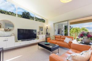 a living room with orange furniture and a large tv at Vista Del Porto - Havelock Holiday Home in Havelock