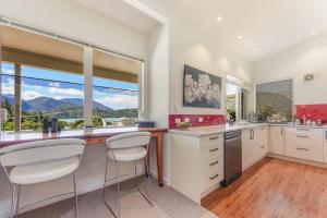 a kitchen with white cabinets and a large window at Vista Del Porto - Havelock Holiday Home in Havelock