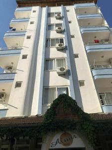 a tall white building with windows and plants on it at Almir Otel in Erdemli