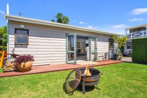 a house with a deck with a fire in the yard at Da Vics - Athenree Holiday Home in Katikati