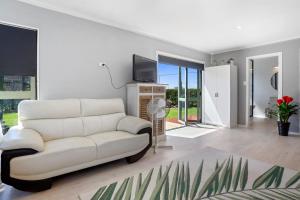 a living room with a white couch and a tv at Da Vics - Athenree Holiday Home in Katikati