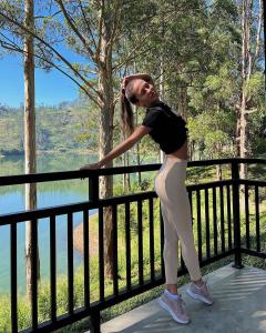 a woman leaning on a fence next to a lake at The Farm Resorts in Hatton