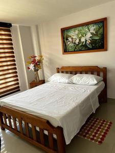 a bed in a bedroom with a painting on the wall at Acogedor apartamento en San Gil. in San Gil